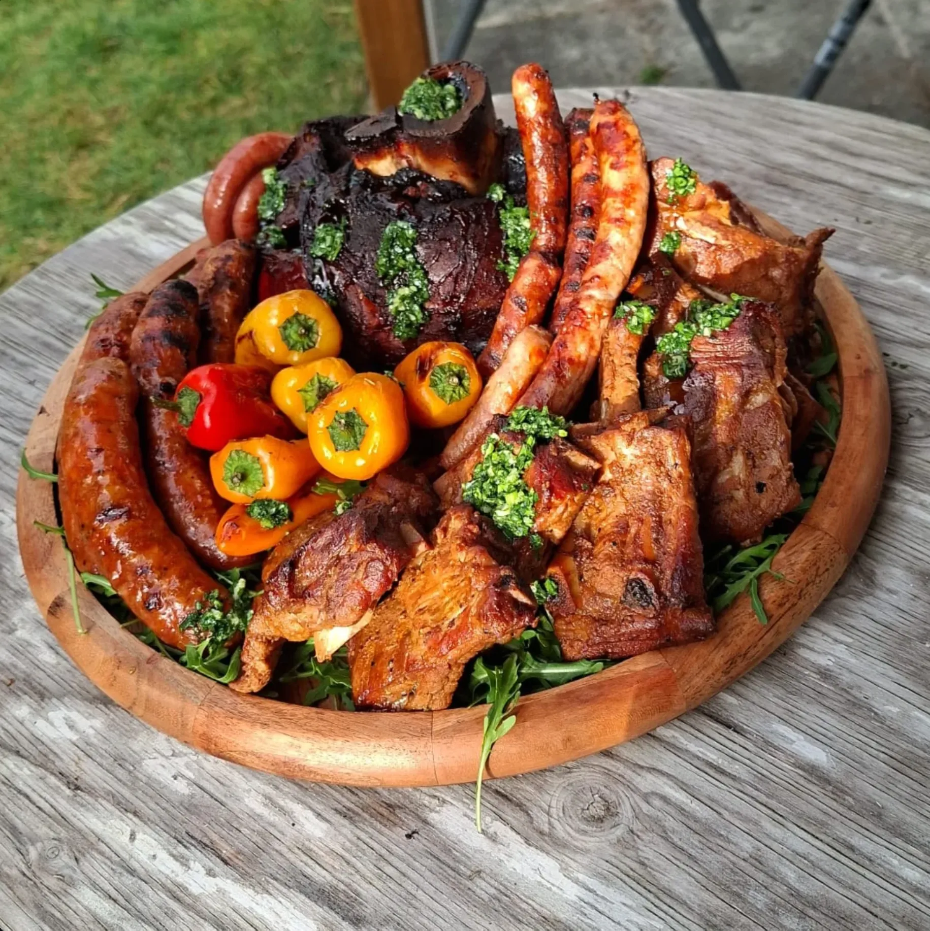 Gemischte Grillplatte mit Rippchen, Haxe und Würsten auf dem Holzteller