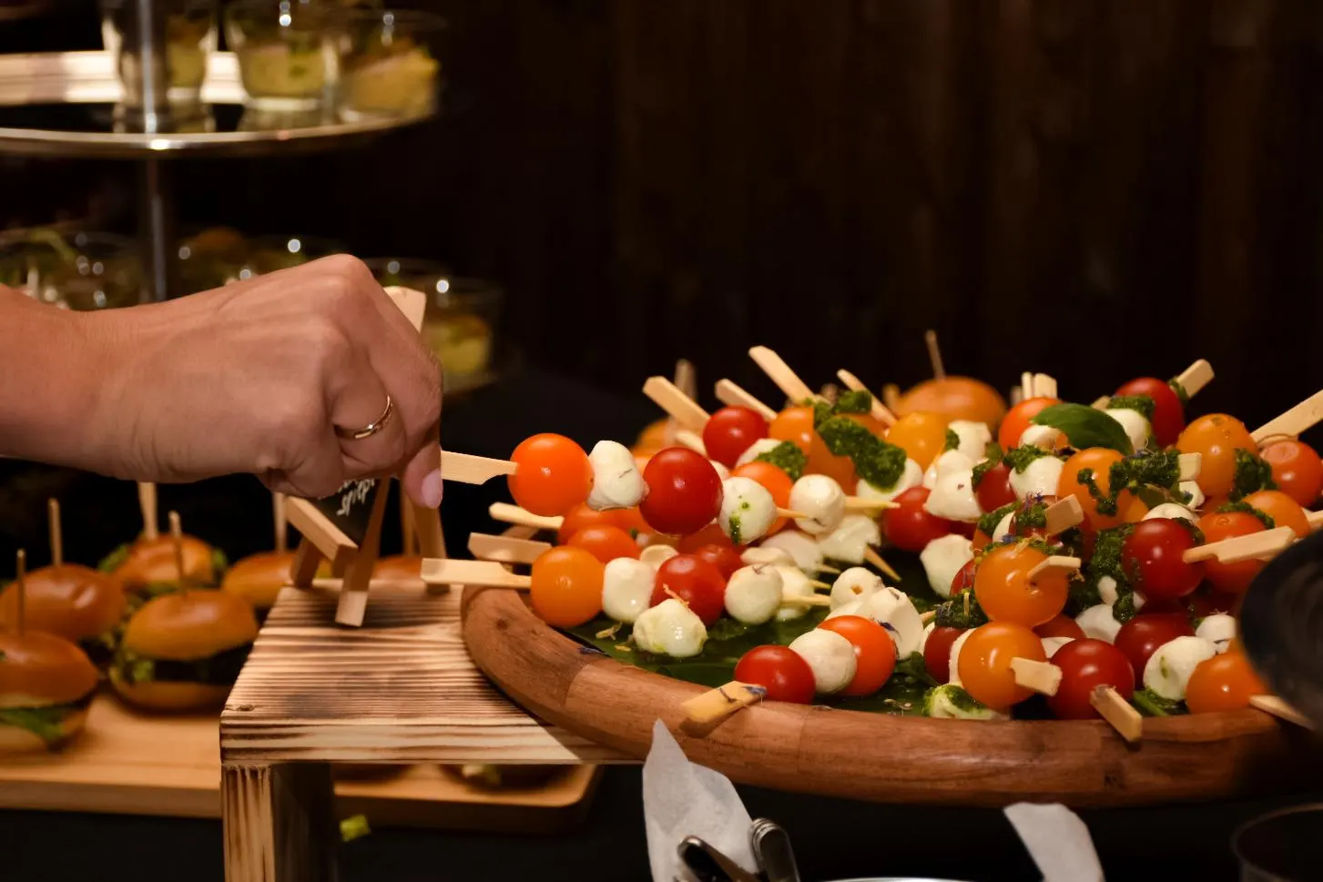 Hand nimmt einen Tomaten-Mozzarella-Spieß